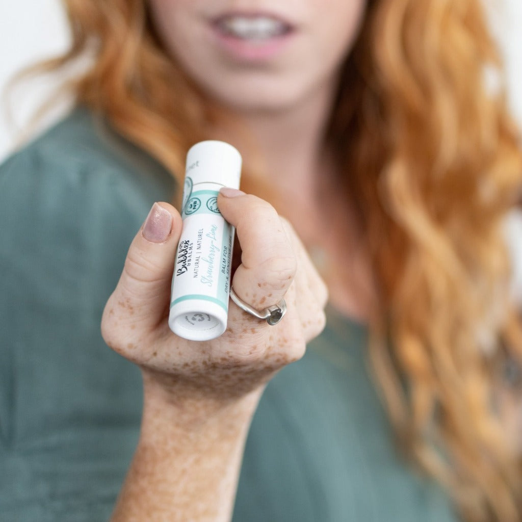 Bubbles &amp; Balms Strawberry Lime vegan lip balm with comfort seal and compostable packaging in the hand of someone with sensitive lips.