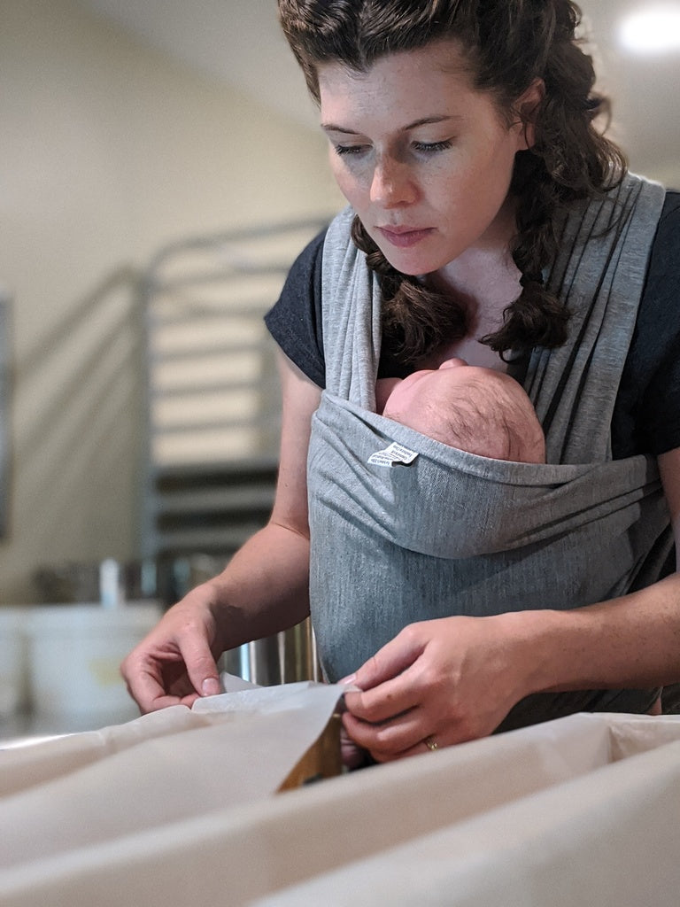 Bubbles & Balms Cofounder Judith Sweeney With Infant Child Strapped To Her As She Preps Product Molds in Her Cosmetic Studio