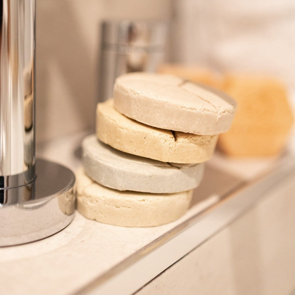 Four Bubbles &amp; Balms solid bubble baths for dry skin stacked on edge of tub.