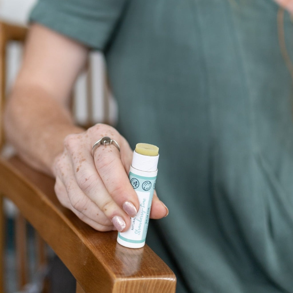 Bottom of Strawberry Lime vegan lip balm for sensitive lips being tapped on a hard surface so the balm easily slips back into the compostable, paper tube.