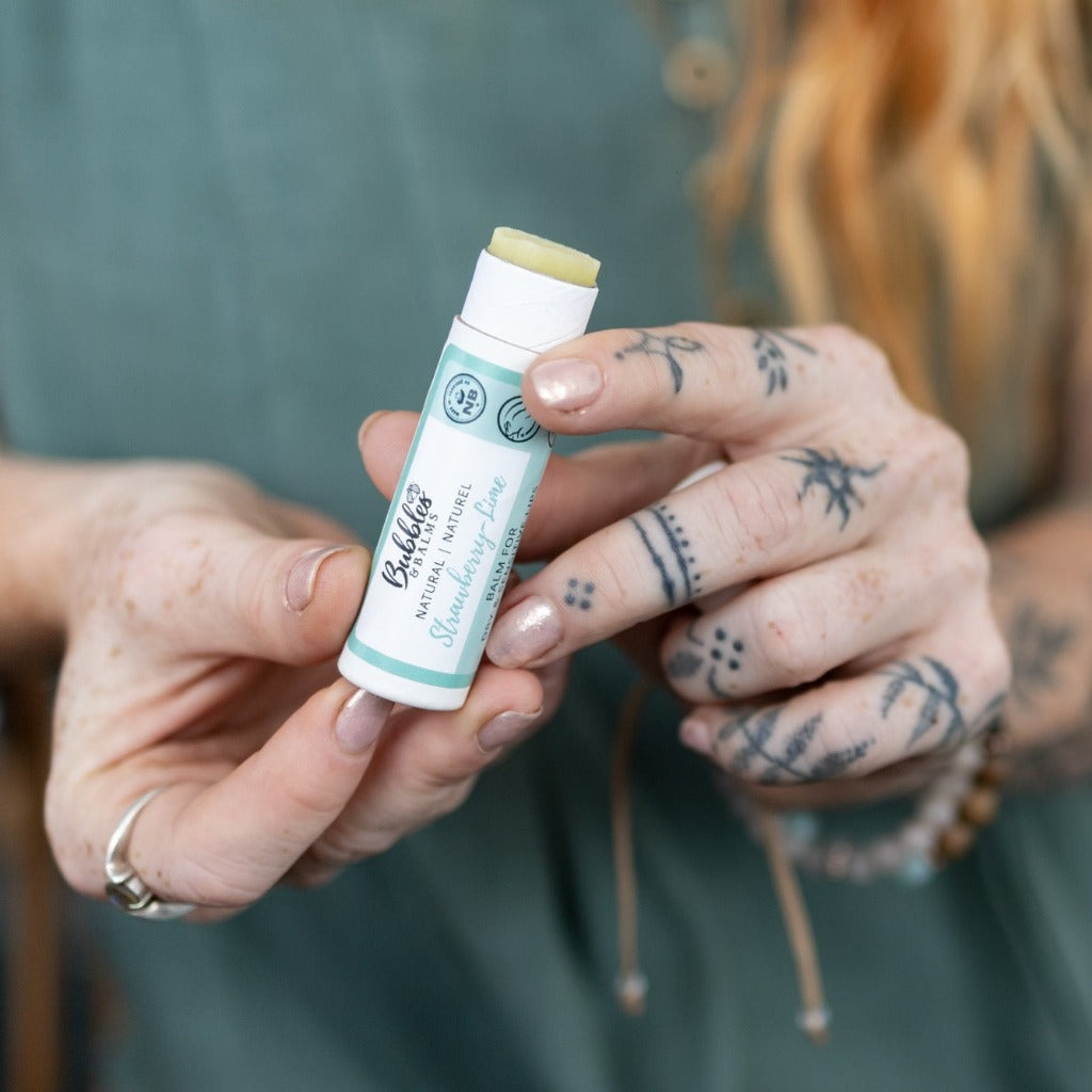 Woman pushing Bubbles &amp; Balms lip balm up from bottom to apply to dry &amp; sensitive lips.