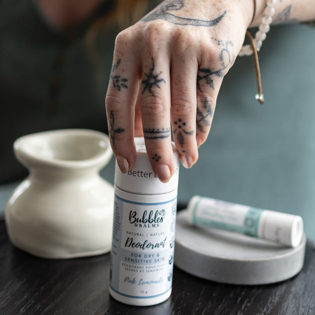 Plant-based and vegan deodorant for sensitive skin being picked up by tattooed hand.