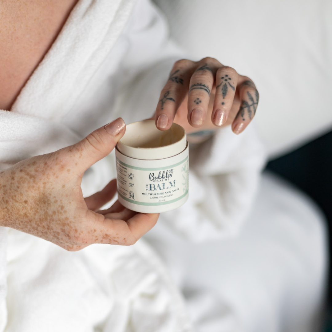 Woman about to apply The Balm, an unscented multipurpose salve infused with power of botanicals from Bubbles & Balms.